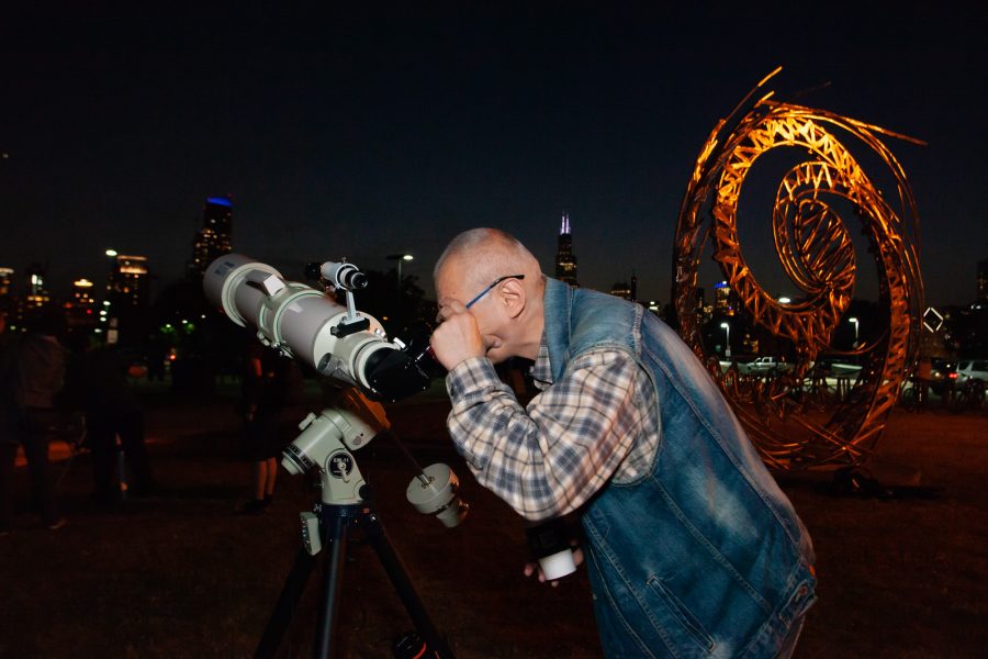 An observer looks up at the night sky through an Adler telescope.