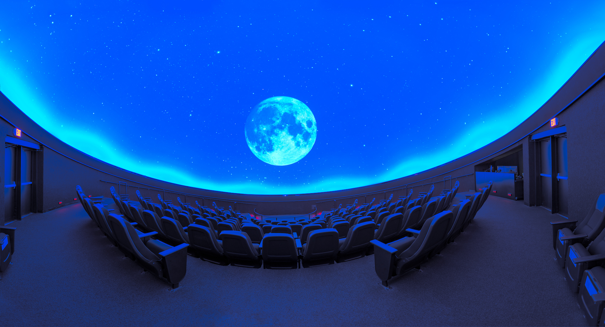 Fish eye shot of the Space Theater empty with blue screen and projection of the moon. Empty theater.