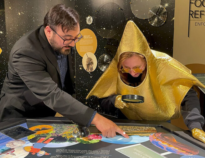 An Adler Educator points out small details that can only be seen through a magnifying lens on the Stargazers Hub table to the Adler Star.