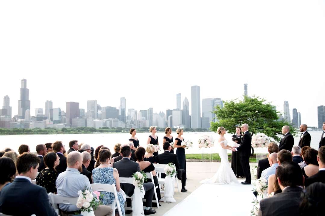 Daytime wedding in the Sundial Plaza with the Chicago city skyline as the backdrop. Bride and groom, attendants and guests can be seen.