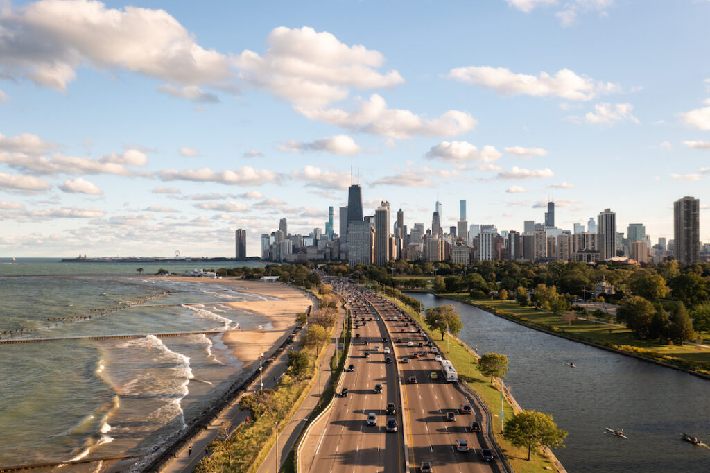 Aerial view of Lake Shore Drive traveling along Lake Michigan with the Chicago skyline in the background.