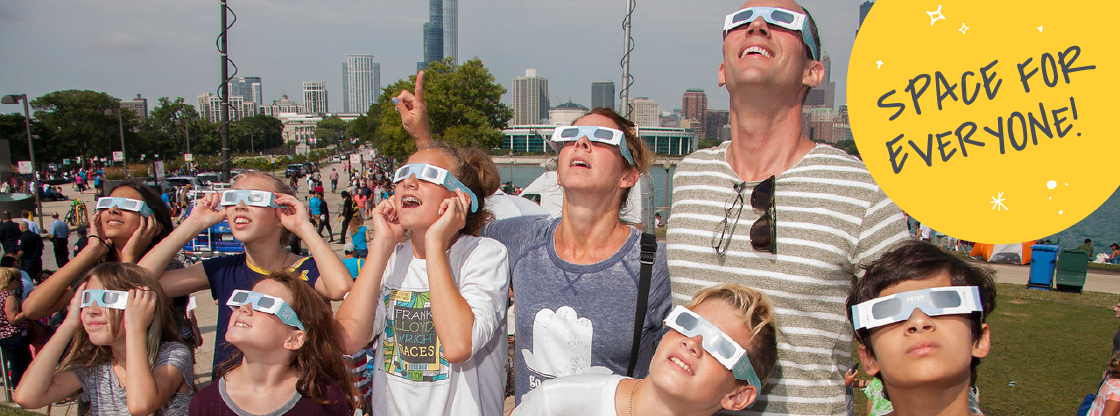 A family looking up at the sky during the 2017 eclipse while wearing their Adler eclipse-viewing glasses.