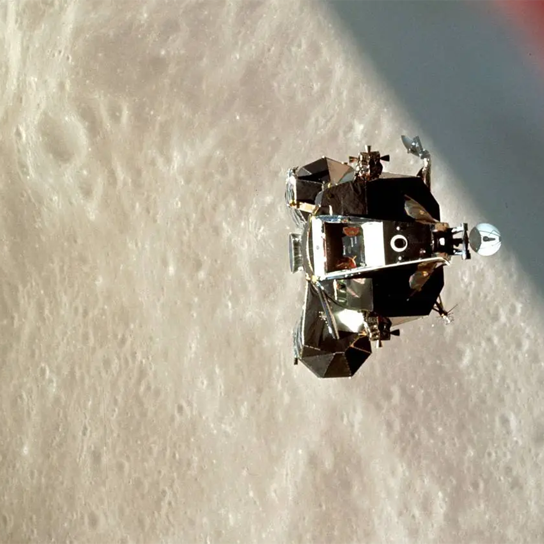 A lunar module floats in space with a close view of the Moon behind it.