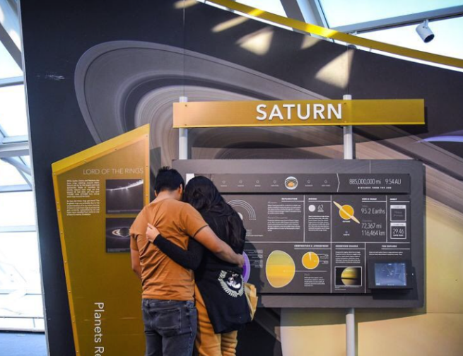 Couple embracing while looking at the Saturn exhibit in Our Solar System, at the Alder Planetarium.