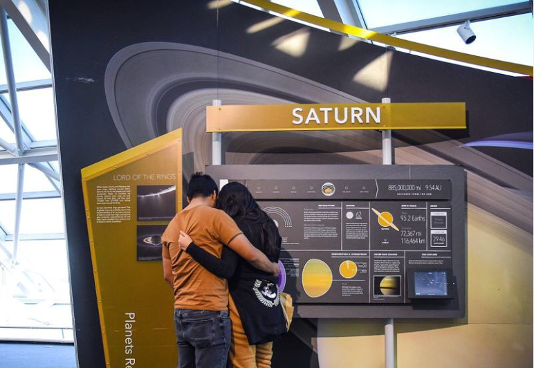 Couple embracing while looking at the Saturn exhibit in Our Solar System, at the Alder Planetarium.