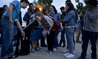 A teen peers into a telescope at an Adler event.