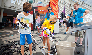 Two young Adler visitors don their excavation gear and search for meteorites in the Adler's Our Solar System exhibition.