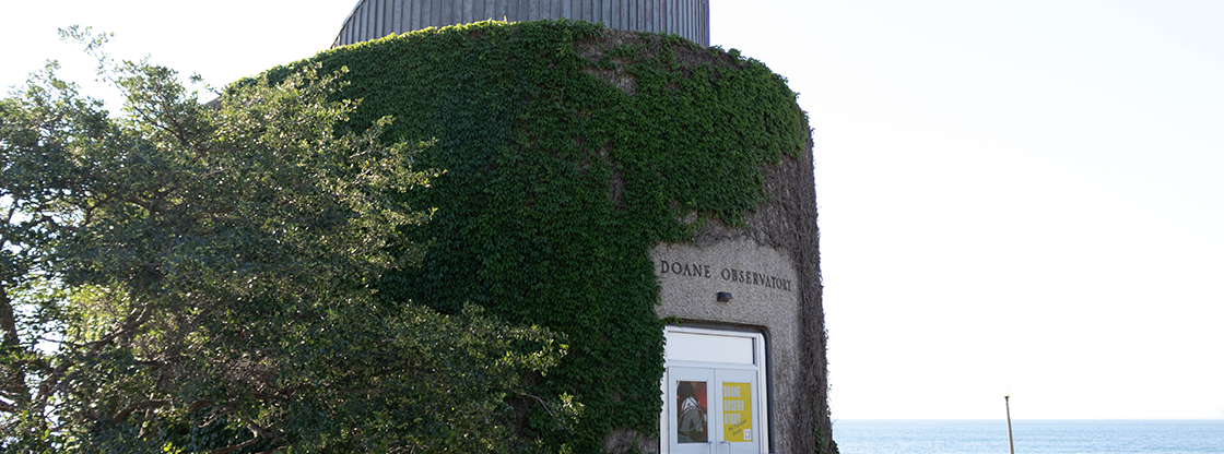 horizontal photo of the Doane Observatory during the day with green ivy covering the building. Picture is taken facing south with Lake Michigan to the right of it.