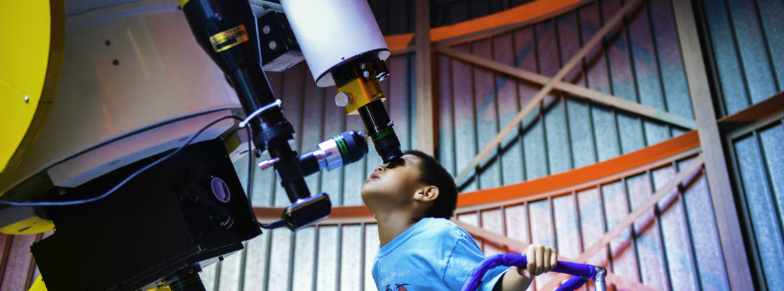 A young boy peers into a telescope in the Adler's Doane Observatory. 