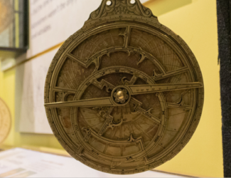 A gold astrolabe hung on a post for people to touch, in the Astronomy in Culture exhibit.