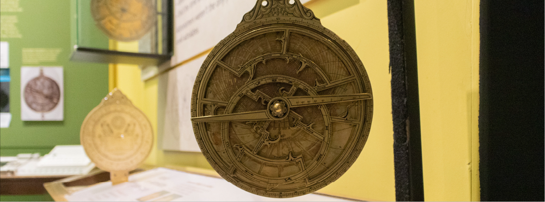 A gold astrolabe hung on a post for people to touch, in the Astronomy in Culture exhibit.