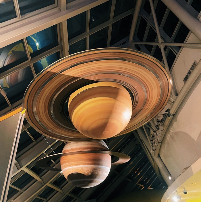 Huge Saturn and Jupiter planet models hanging from a glass ceiling.