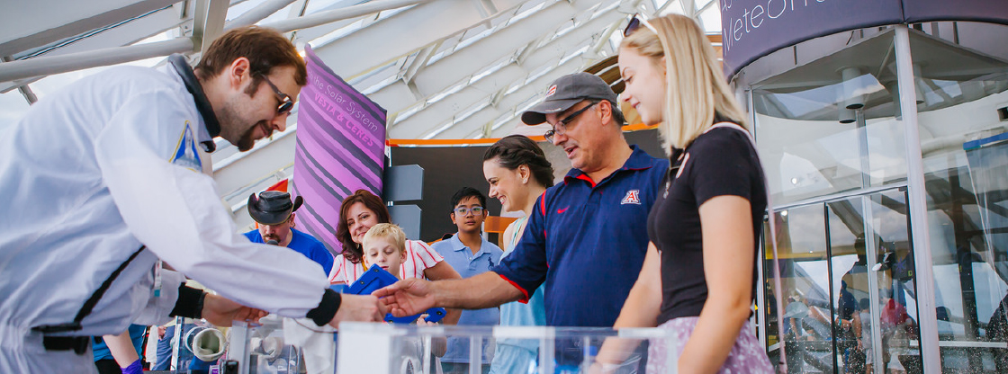 A group of Adler guests interacting with a volunteer on an experiment. 