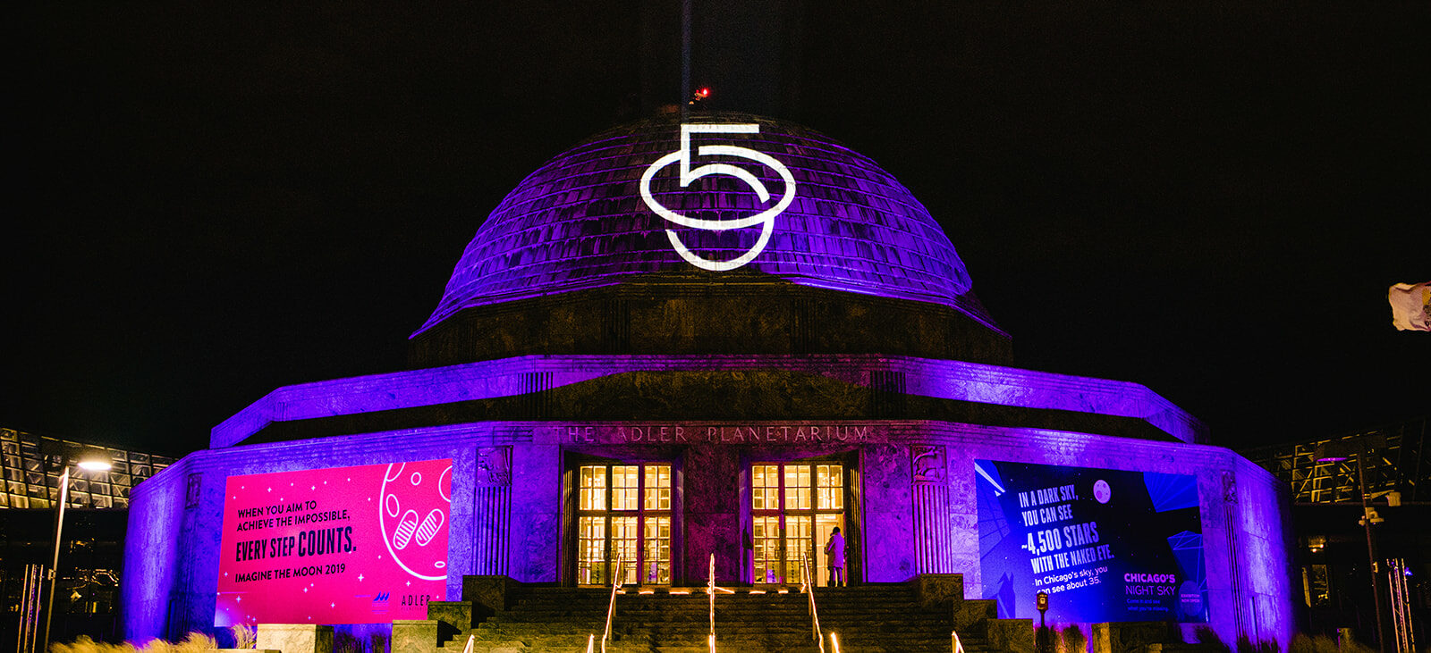 Exterior of the Adler Planetarium at Night featuring a "50" projection on the dome roof for a branded event.