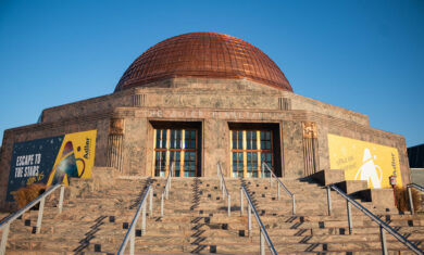 Front exterior of the Adler Planetarium with a blue sky.