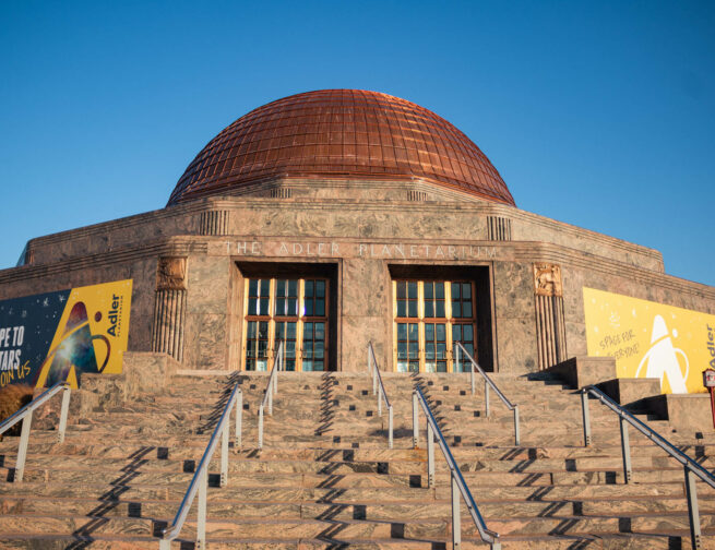 Front exterior of the Adler Planetarium with a blue sky.