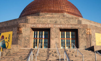 Front exterior of the Adler Planetarium with a blue sky.