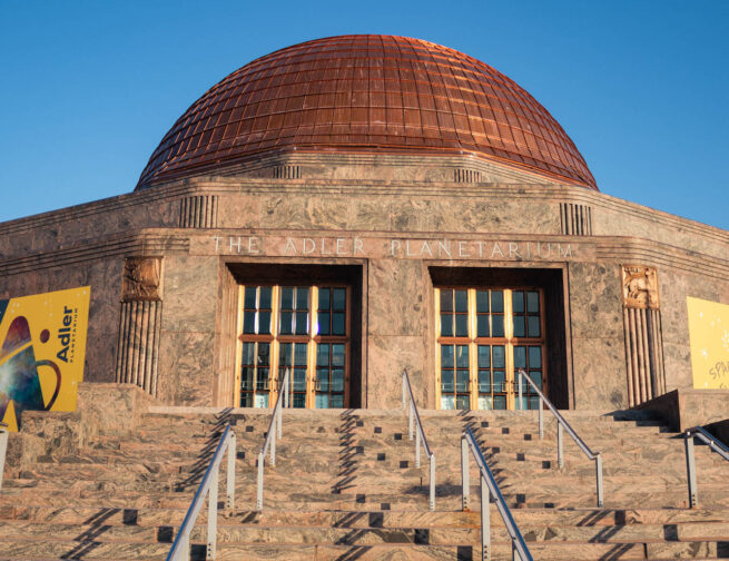 Front exterior of the Adler Planetarium with a blue sky.