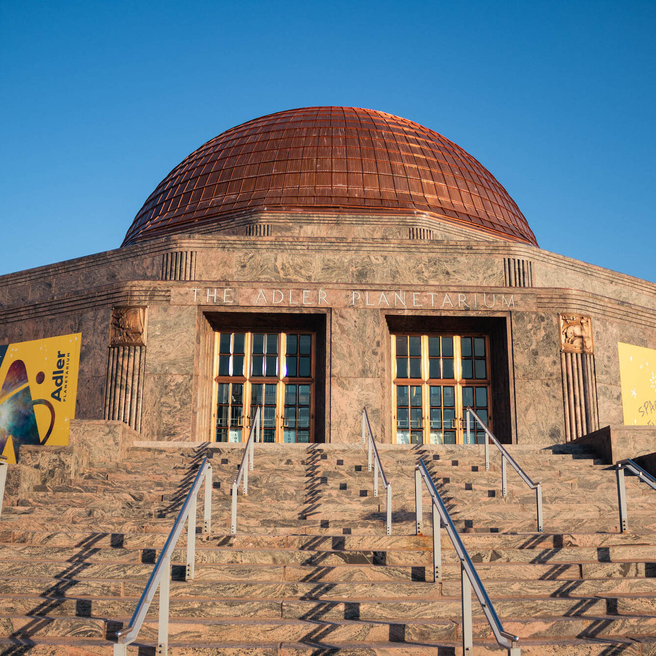 Front exterior of the Adler Planetarium with a blue sky.