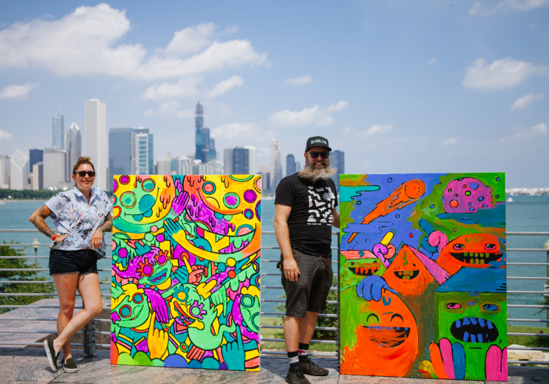 Lauren Asta (left) and Shawn Smith (right) pose with their completed Moonshot Murals painted by Adler guests during Moon Bash on July 20, 2019.