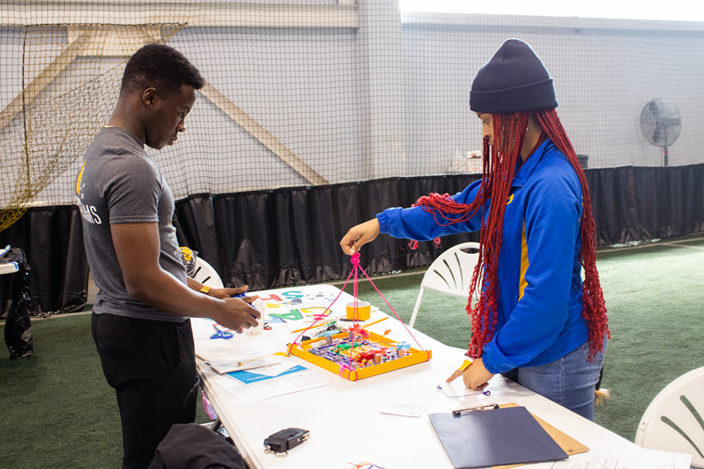 Two students admiring their completed airship, one holding the airship, the other holding the controller.