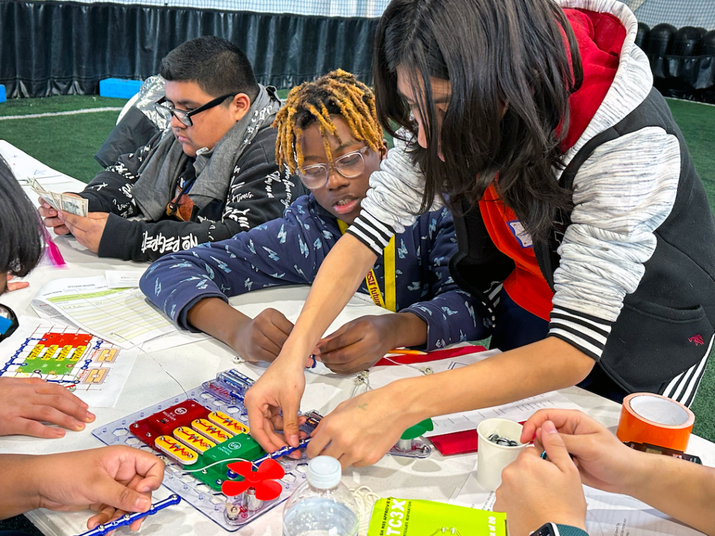 A team of students working together to assemble their airship's base electronic circuit board.