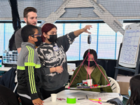 A group of students at the Adler Planetarium's 2023 Operation Airlift, weighing their airship with the guidance of an Adler STEM mentor.