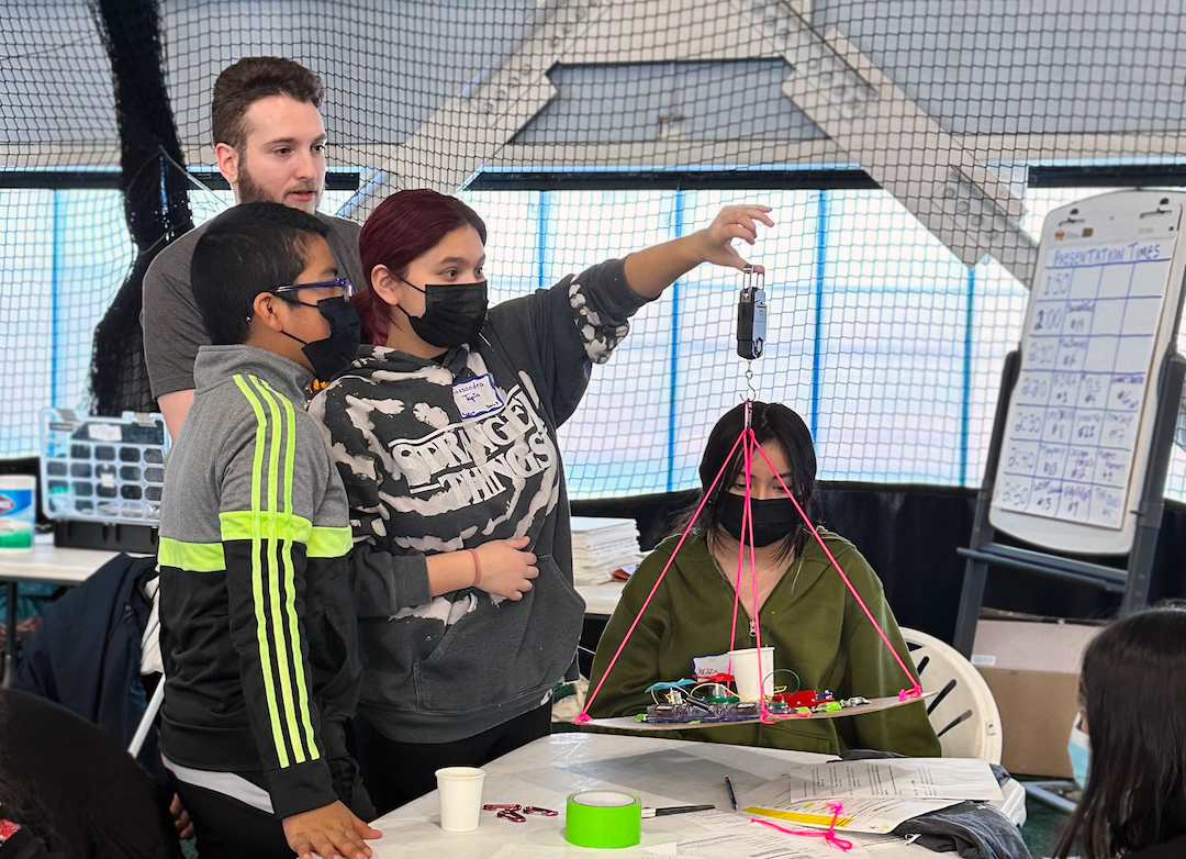 A group of students at the Adler Planetarium's 2023 Operation Airlift, weighing their airship with the guidance of an Adler STEM mentor.