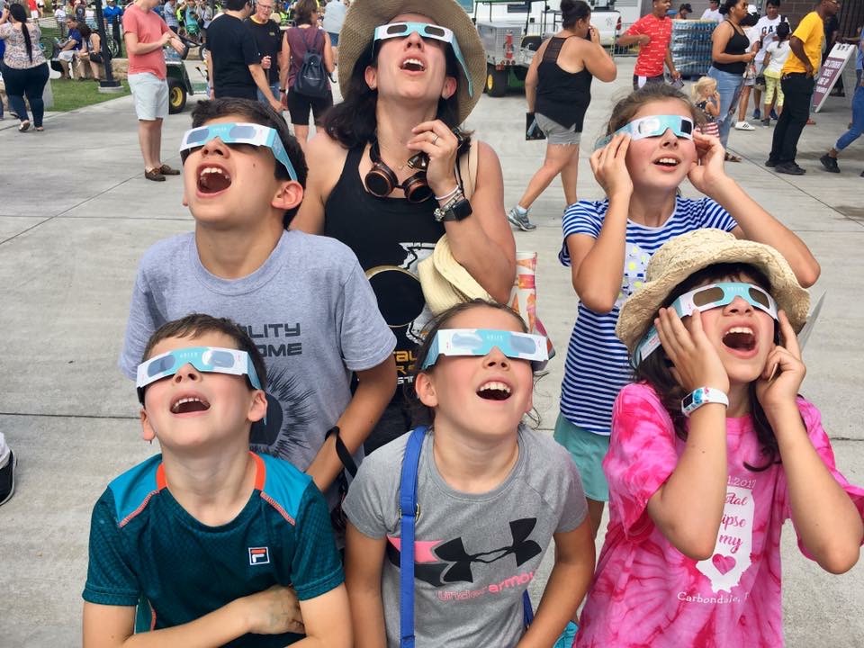 Photo of family looking up safely at the Sun during Adler's Eclipse Fest in August 2017.