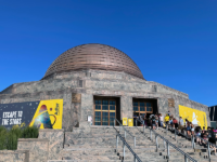The Adler Planetarium on a sunny, summer day, with a line of guests on the museum steps.