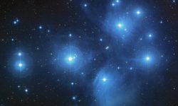 This is an image of the Pleiades star cluster. You can see in this image faint clouds of bluish nebulae and dozens of bright stars scattered in the distance.