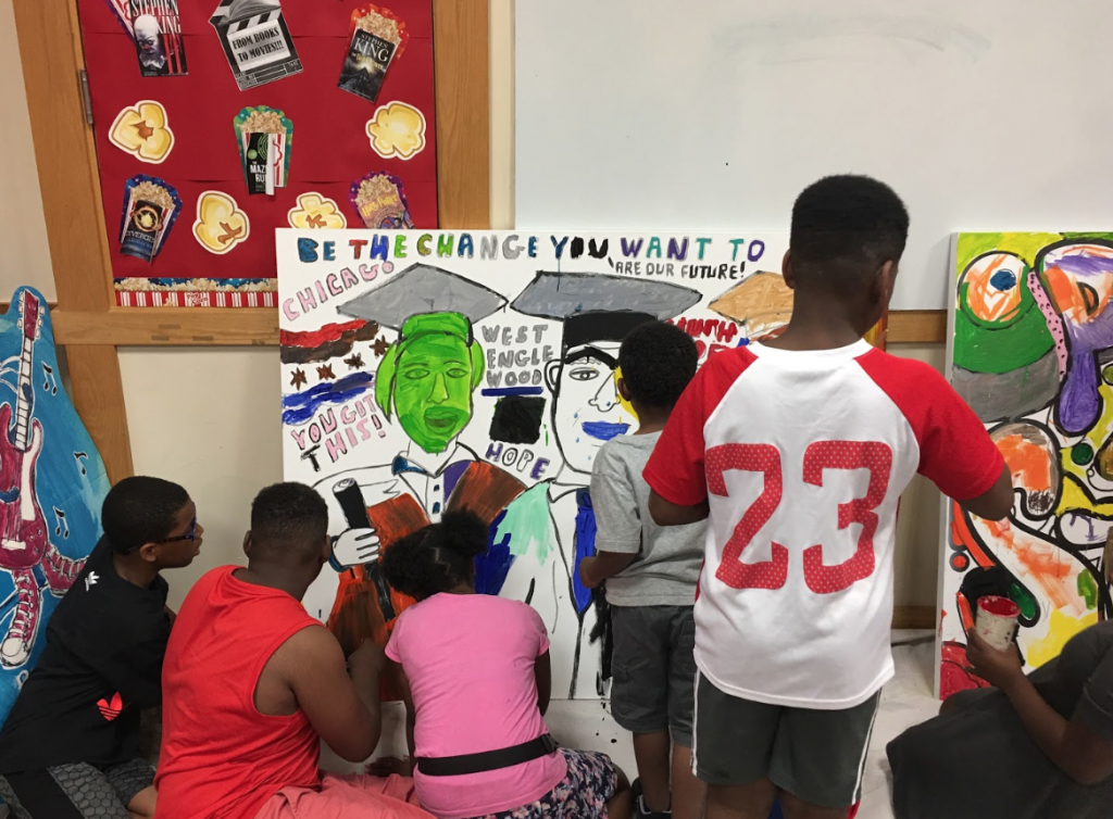 A picture of West Englewood you painting a canvas that says, "Be the change you want to be," by street artist, Don't Fret.