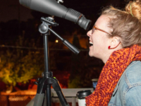 An attendee looking through a telescope during a ‘Scopes In The City neighborhood event with the Adler Planetarium.
