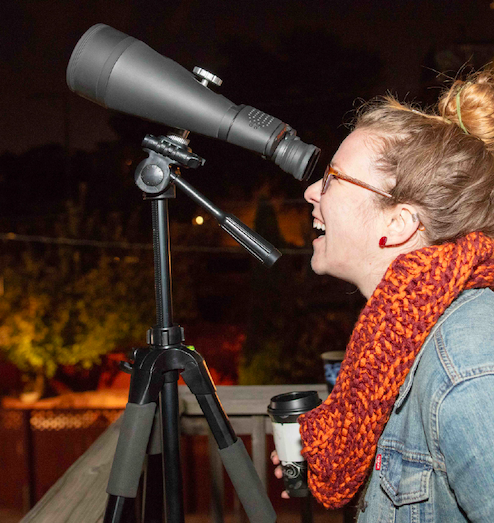 An attendee looking through a telescope during a ‘Scopes In The City neighborhood event with the Adler Planetarium.