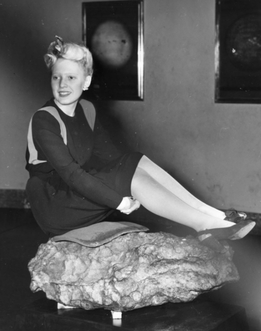 A woman sitting on a meteorite at the Adler Planetarium