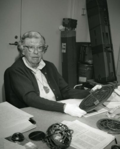 Madge Webster in her element, surrounded by historical scientific instruments, and holding an astrolabe while wearing another one in a necklace (Adler archives).