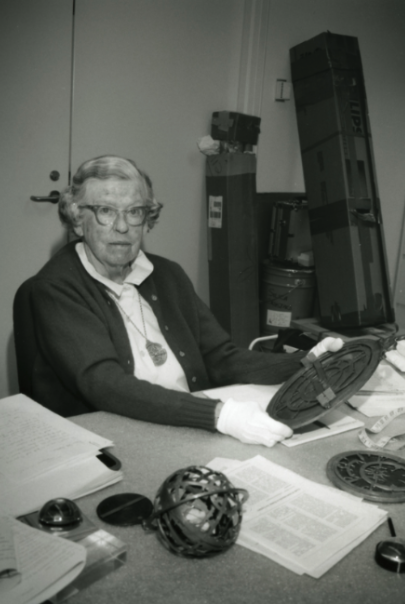 Madge Webster in her element, surrounded by historical scientific instruments, and holding an astrolabe while wearing another one in a necklace (Adler archives).