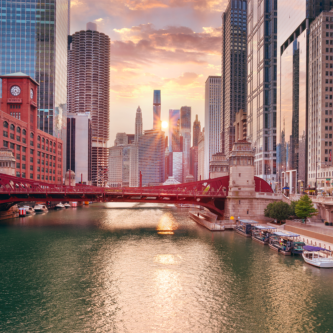 Image of downtown Chicago during the autumn equinox, with the Sun setting in between skyscrapers in the background and the Chicago river in the foreground.