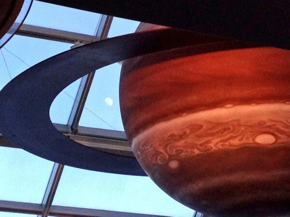 A photo of the Moon peaking through the window panels inside the Adler Planetarium's Solar System Gallery.