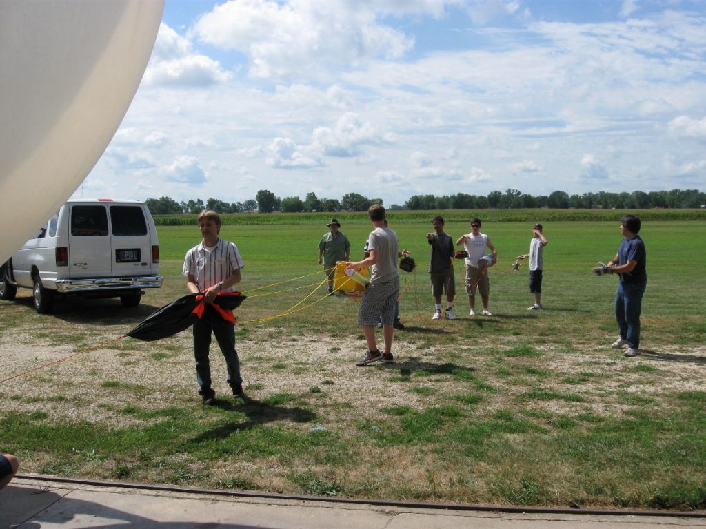 Spencer Gore (left foreground, black and white stripped shirt) and Far Horizon teens in 2011 prepare a balloon for a payload launch.