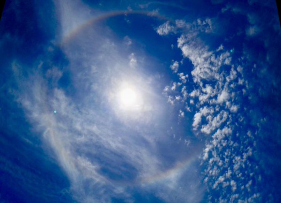 Ice crystals in the atmosphere bending light around the Sun to form a rainbow.