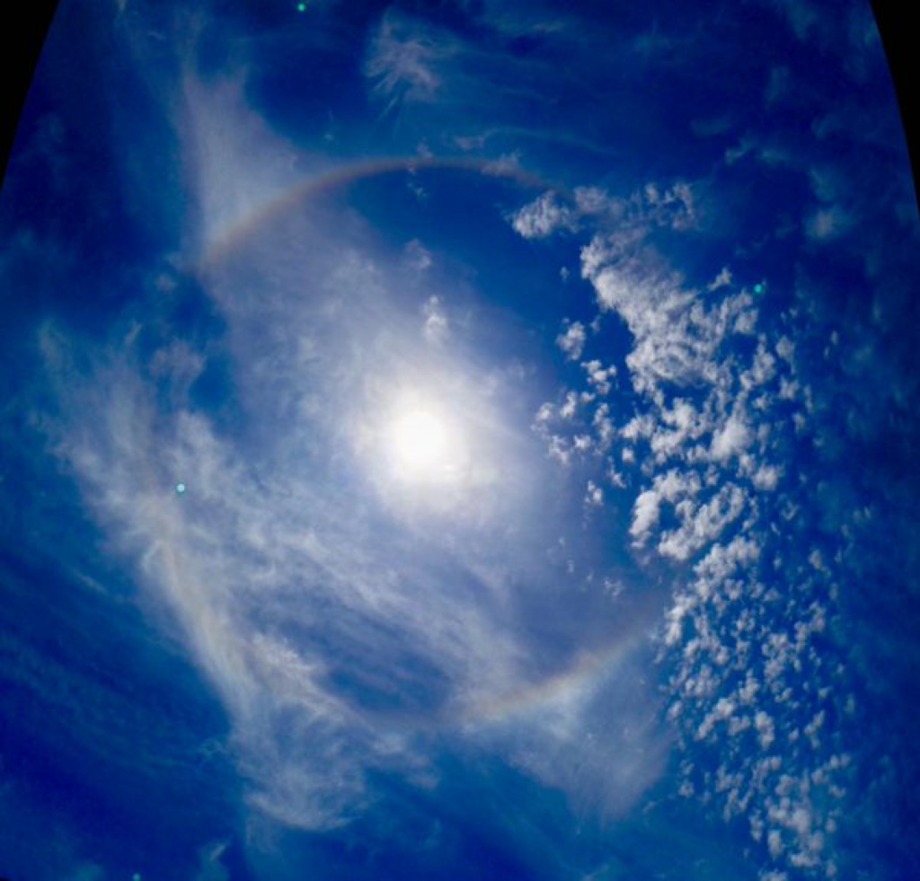 Ice crystals in the atmosphere bending light around the Sun to form a rainbow.