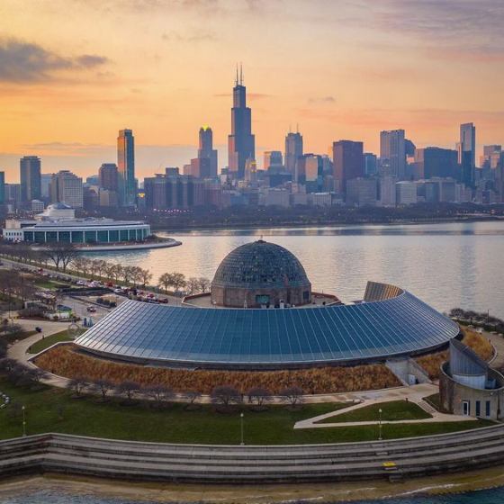 Sunset shot of the Adler Planetarium via a drone with the Chicago skyline in the background