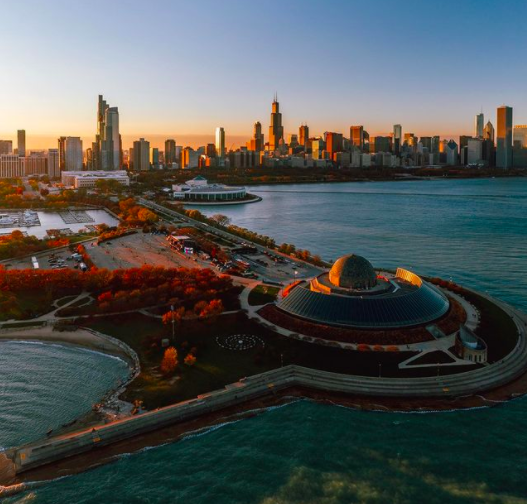 Museum Campus showing an aerial view of the Adler Planetarium, Shedd Aquarium, Field Museum, and Chicago skyline in the fall at sunset.