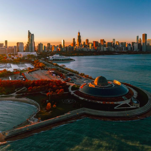 Museum Campus showing an aerial view of the Adler Planetarium, Shedd Aquarium, Field Museum, and Chicago skyline in the fall at sunset.