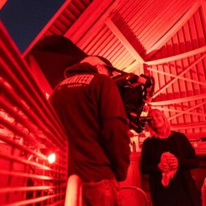 Reflecting telescope with two people, one looking through the telescope.