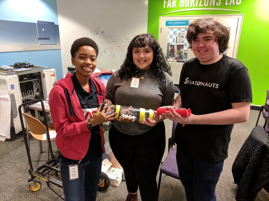 From left, Adler teens Carmen Jones, Giovanna Rossi, and Jack Morgan show off an important piece of technology they all helped create. Listen to the Aquarius Project Podcast to find out what it is!