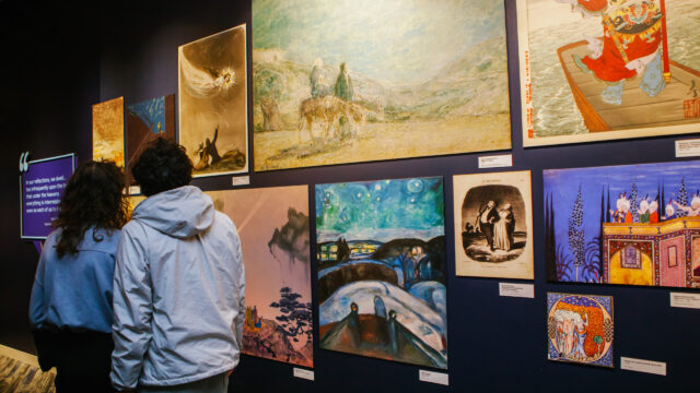 Two guests admire a display of paintings depicting stars and the sky