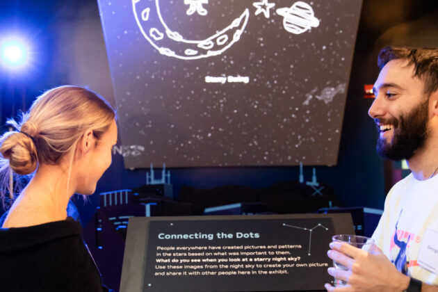 A young man and woman interact with an exhibit called “Connecting the Dots”