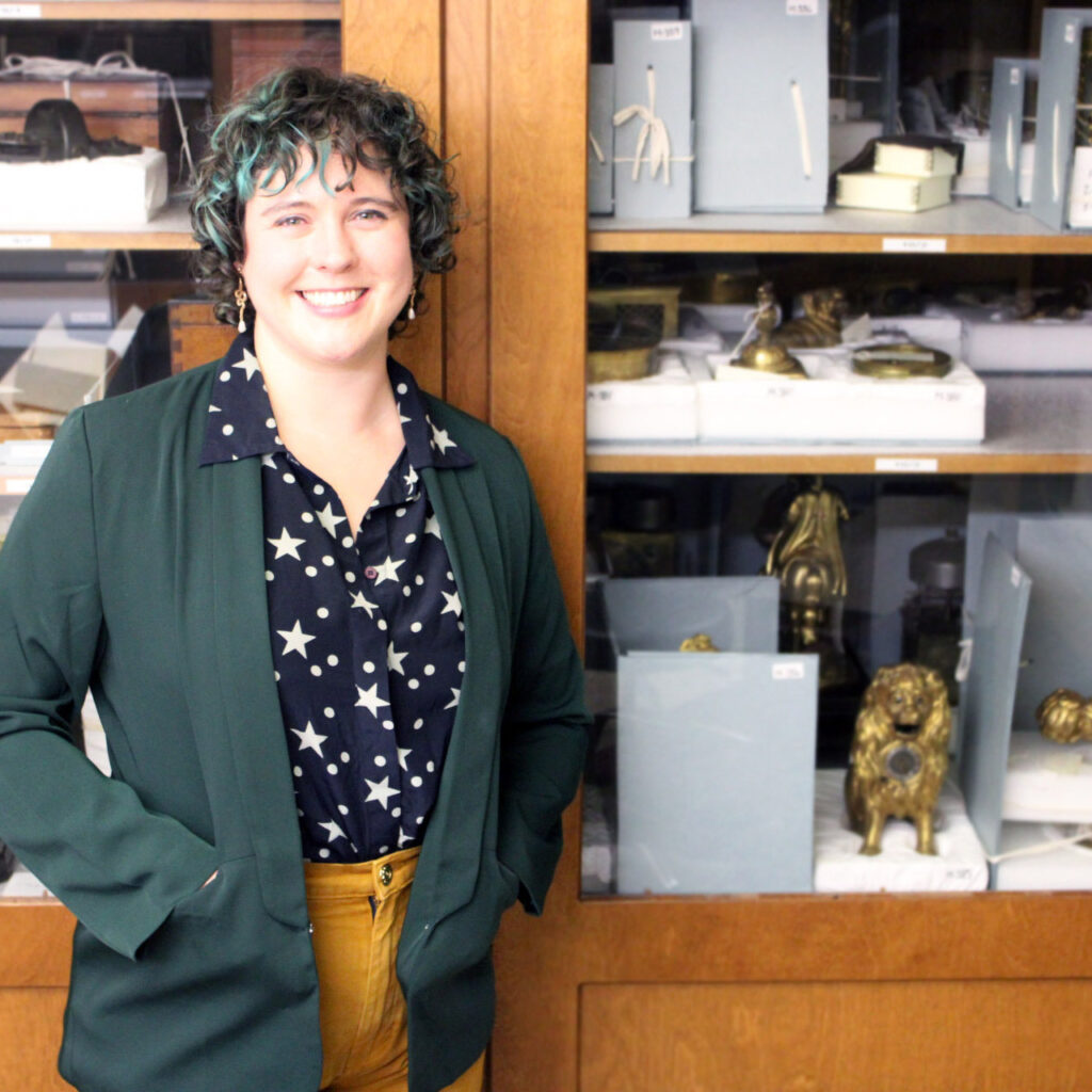 Dr. Katie Boyce-Jacino standing next to a cabinet full of Adler Planetarium collections objects.